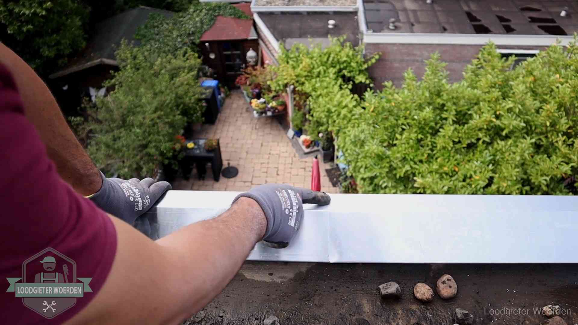 Vakman plaatst een daktrim op de dakrand van een woning in Woerden