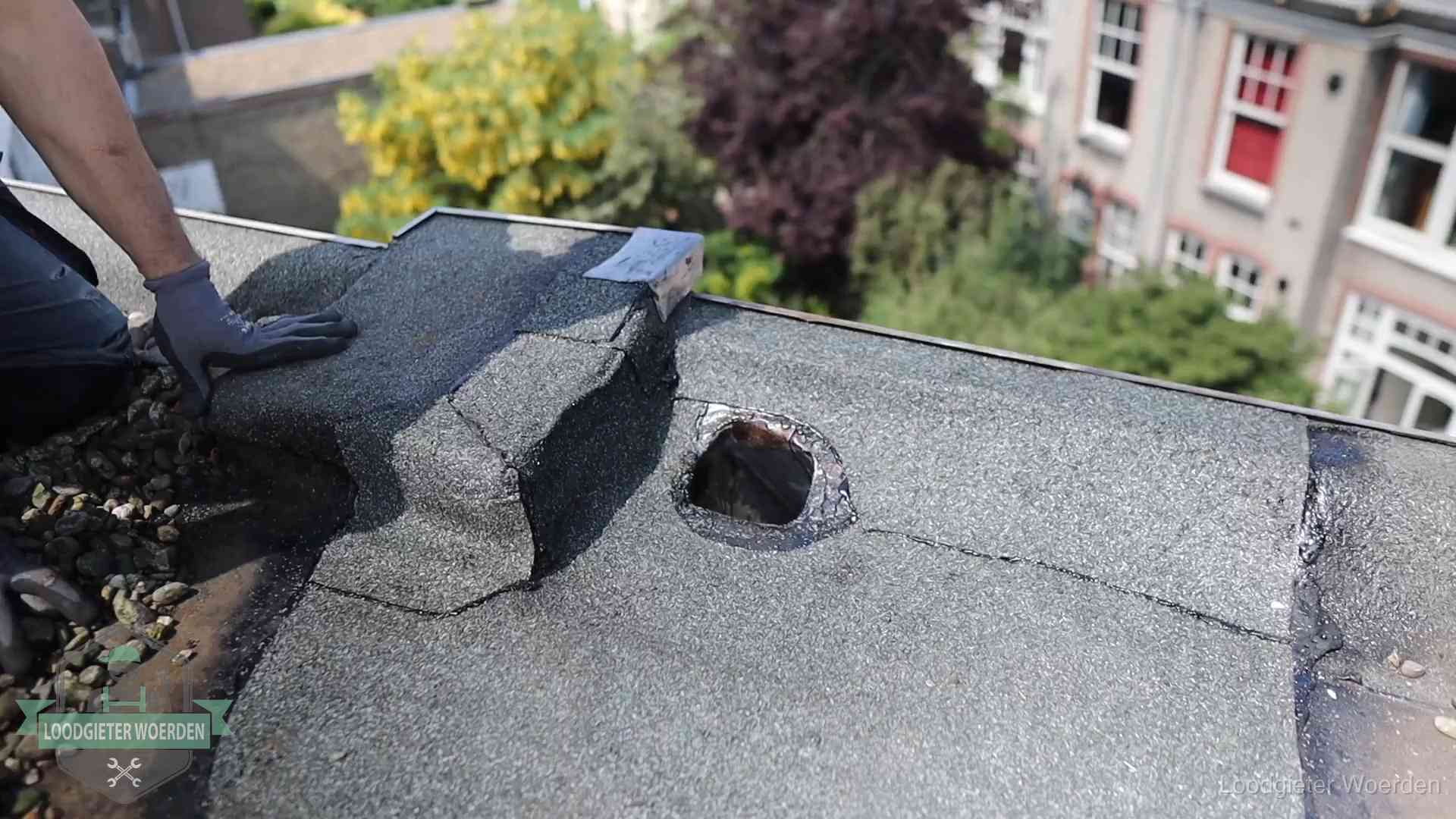 Loodgieter inspecteert een beschadigd bitumen plat dak tijdens een daklekkage-inspectie in Woerden