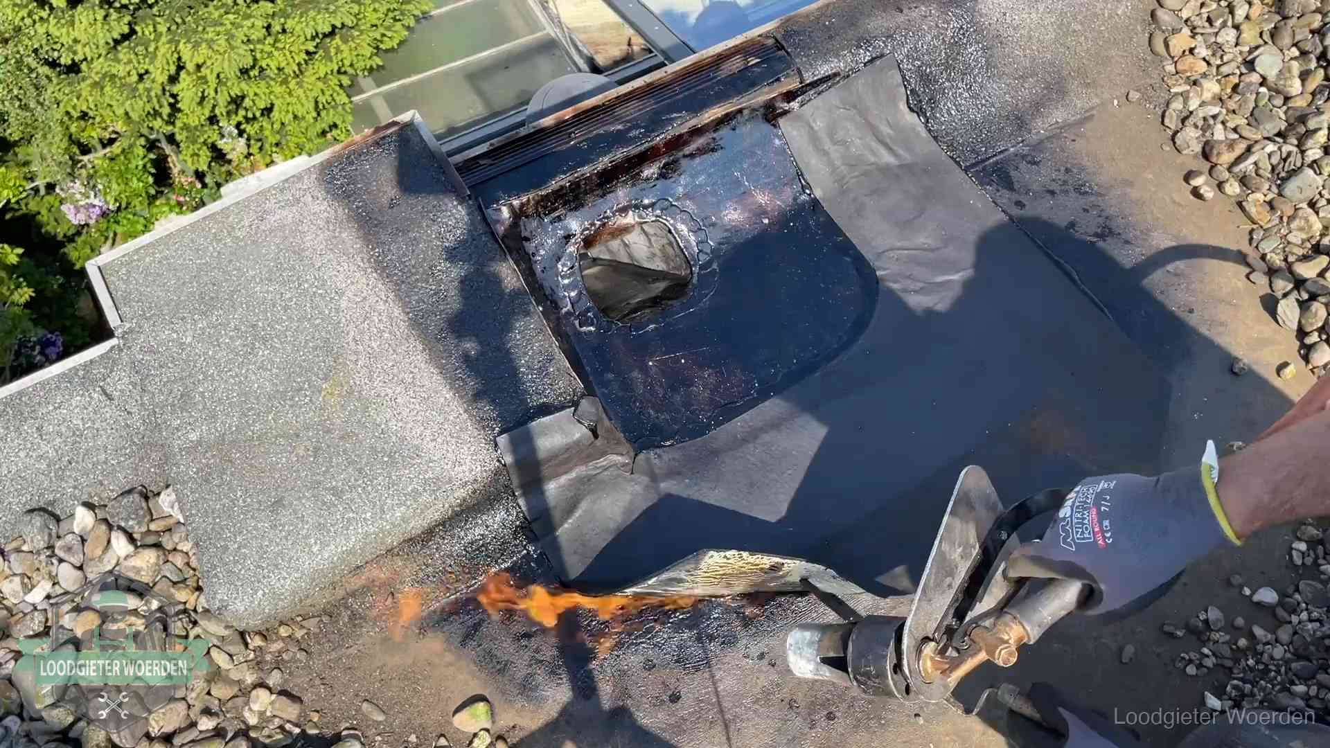 Dakdekker brandt bitumen rond een doorvoer tijdens een daklekkage-reparatie in Woerden
