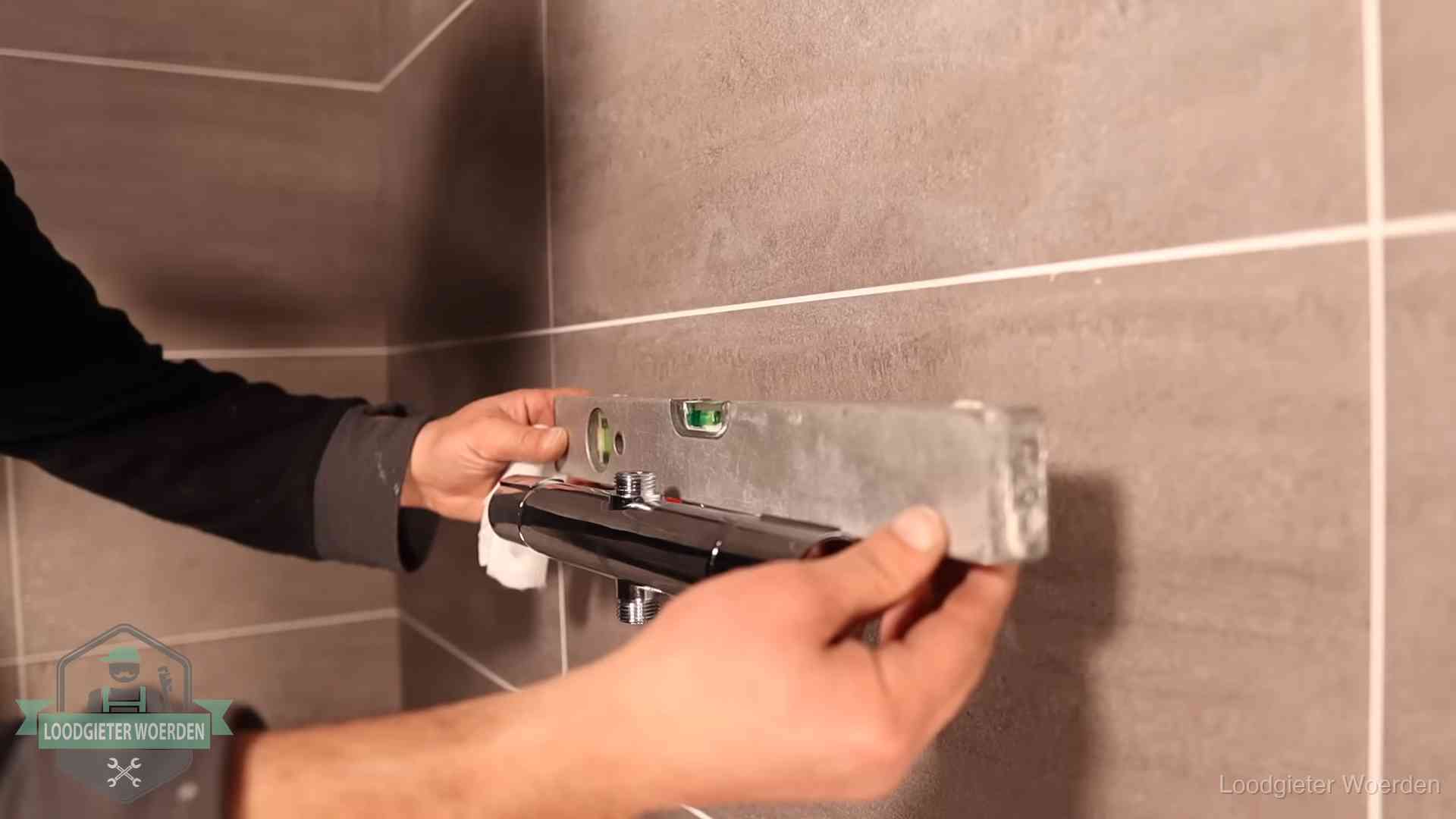 Loodgietersbedrijf voor sanitair in Woerden Loodgieter lijnt een douchekraan uit met een waterpas in een woning in Woerden