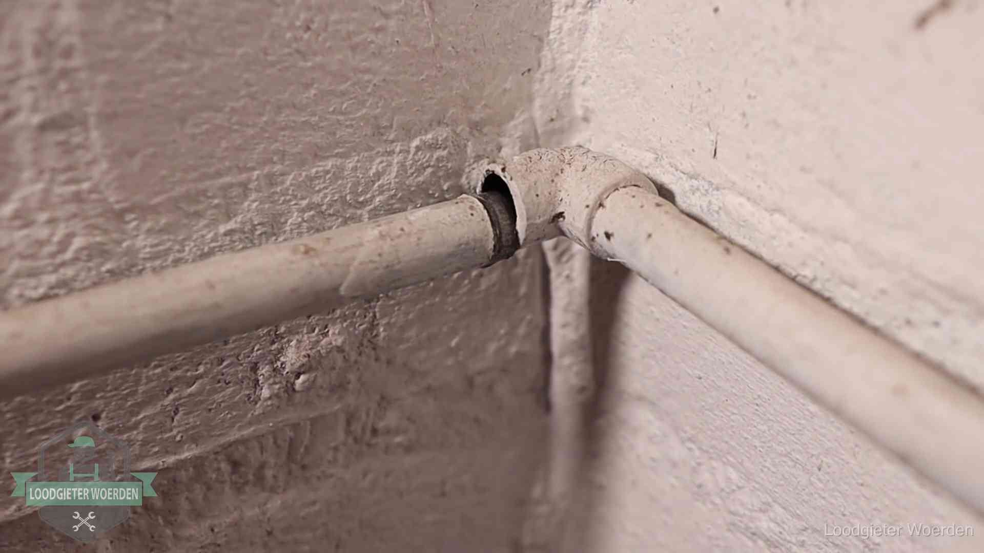 Oude geverfde waterleiding met een losliggende fitting in een woning in Woerden