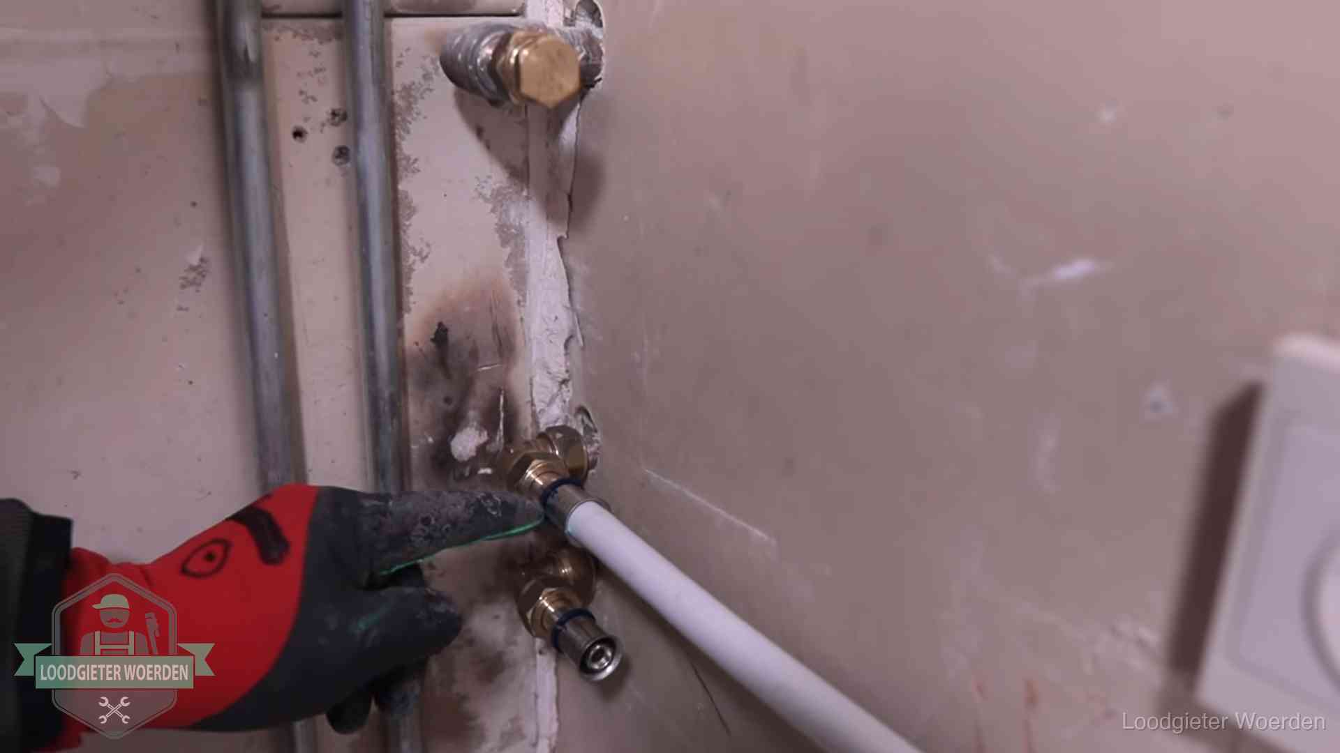 Garantie op loodgieterswerk in Woerden Loodgieter wijst de persfitting op nieuwe muuraansluitingen aan in een woning in Woerden
