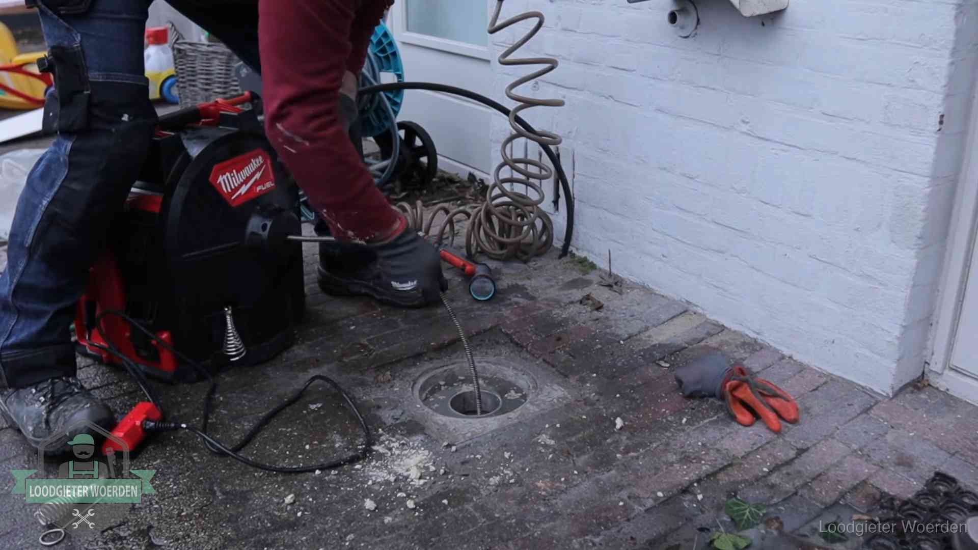 Prijs van een rioolontstopping in Woerden Spiraalmachine bij een ontstoppingsputje in de bestrating in Woerden