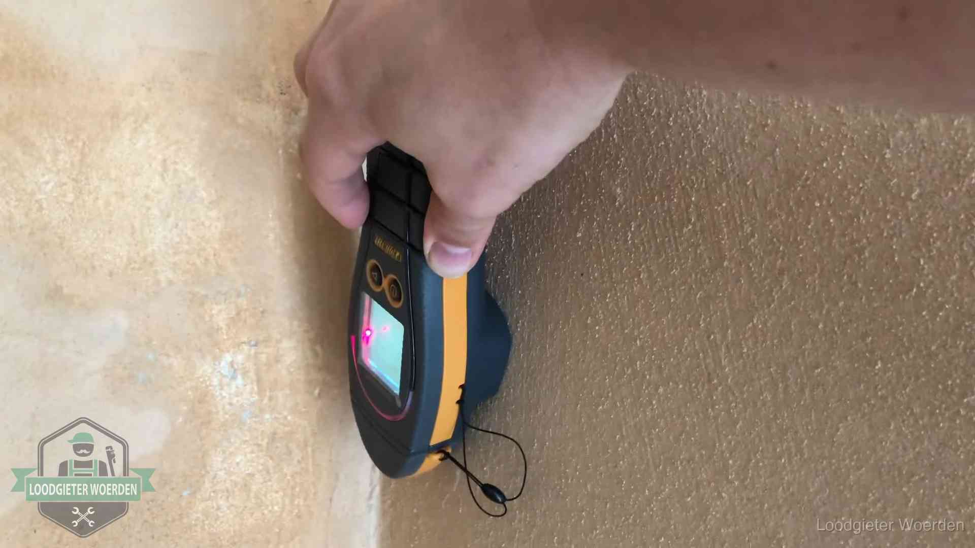 Vochtmeter tegen een muur met vochtplekken tijdens het opsporen van een daklekkage in Woerden