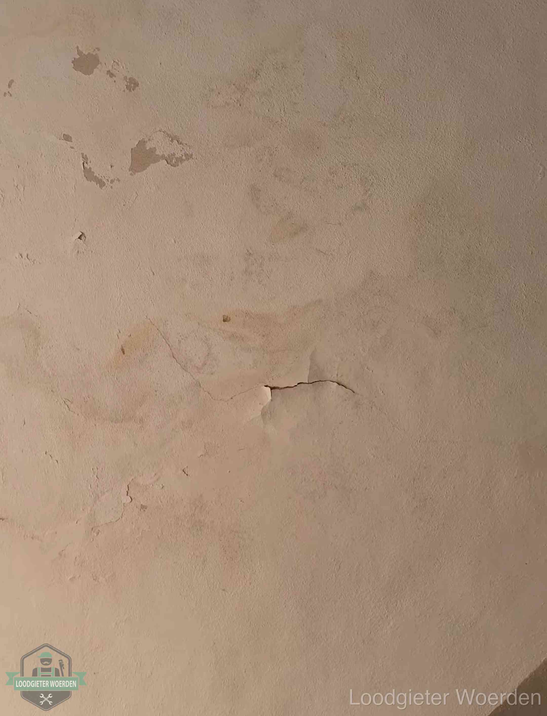 Vochtkringen en afbladderende verf op een plafond in Woerden, schade voor het meetrapport en de verzekering